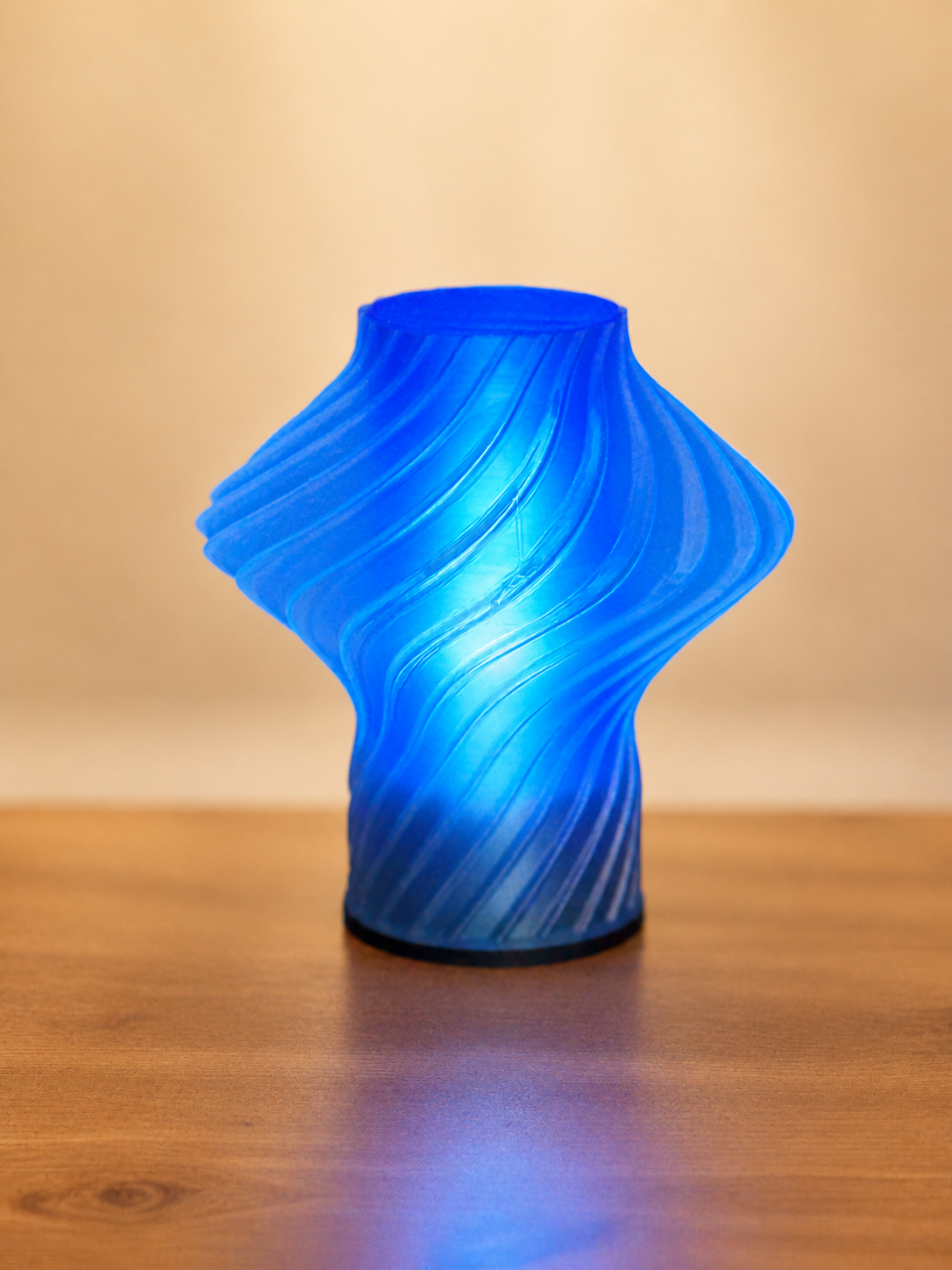 Carla Table Lamp illuminated in blue, featuring a sculptural geometric design and modern 3D printed shade.