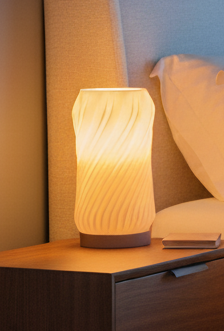 Minimalist spiral lamp with a sculptural design casting a soft ambient glow.